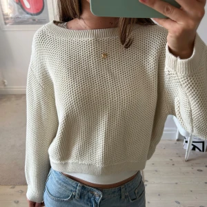 Beige stickad tröja med grov struktur - Säljer en beige stickad tröja med grov struktur och rund halsringning. Tröjan har en avslappnad passform och långa ärmar. Perfekt att slänga på sig över ett linne eller t-shirt. Ribbstickade muddar vid ärmslut och nederkant.