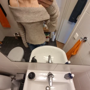 Beige ribbad offshoulder stickad tröja - Superfin beige stickad tröja från H&M med ribbat mönster och bred offshoulder-krage. Sitter tajt och har långa ärmar. Perfekt för dig som vill ha en mysig men ändå snygg look. Passar till jeans eller kjol för en chill vibe.