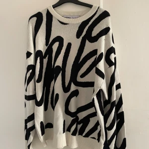 Vit och svart tröja från Bershka - Säljer en vit tröja från Bershka med stora svarta grafiska mönster. Tröjan har rund halsringning, långa ärmar och ribbade muddar. Skön passform och perfekt för dig som gillar statement-plagg med streetkänsla.