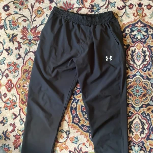 Under Armour Byxor - svart under armour mjukis med skönt stretchigt material, reflekterande logga på fram och baksidan, köpt från second hand så kan inte garantera äkthet. passar mig som har storlek M på byxor.