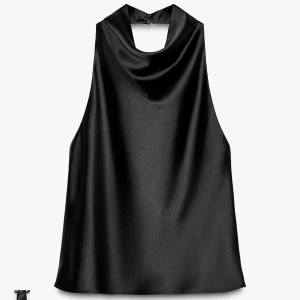 Svart satintopp med hög hals - Säljer en svart ärmlös topp i glansigt satinmaterial med hög hals och knapp i nacken. Toppen har en lös passform och är perfekt för dig som gillar stilrena och trendiga plagg. Snygg att matcha med både jeans och kjol.