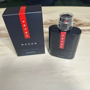 Prada Luna Rossa Ocean EdP 100ml - Prada Luna Rossa Ocean Eau de Parfum i en snygg mörkblå flaska med röd detalj och metallisk spraykork. Doften är maskulin och modern, perfekt för dig som gillar exklusiva parfymer. Flaskan rymmer 100 ml och kommer i originalkartong.