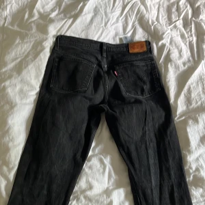 Svarta Levi's 511 jeans skinny fit - Svarta Levi's 511 jeans med klassisk femficksdesign och skinny fit. Jeansen har svarta sömmar, kopparfärgade nitar och Levi's ikoniska läderpatch bak i midjan. Tillverkade i jeansmaterial med en smal passform hela vägen ner.