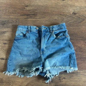 Blåa jeansshorts 💞 - Säljer ett par blåa oanvända jeansshorts i storlek 34! De är högmidjade med råa, fransiga kanter och klassisk femficksdesign!! 😊💞💞
