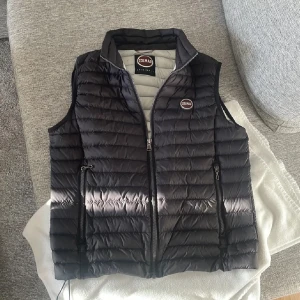 Colmar väst - Snygg svart dunväst från Colmar med quiltad design och hög krage. Västen har två dragkedjefickor framtill och en diskret logga på bröstet. Perfekt att slänga över en hoodie eller tröja för extra värme. Stängs med dragkedja hela vägen upp. Storlek S. Vi kan diskutera om pris hör bara av dig 