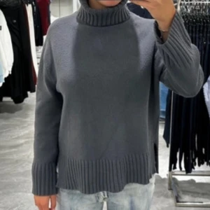 Grå polotröja med ribbade detaljer - Mysig grå polotröja med hög krage och breda ribbade muddar vid ärmslut och nederkant. Säljer då den inte riktigt satt som jag ville. 