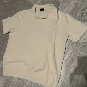 Vit pikétröja i silke från Massimo Dutti - Klassisk vit pikétröja från Massimo Dutti i 100% silke. Tröjan har korta ärmar, krage och ribbade muddar vid ärmslut och nederkant. Perfekt för en clean och stilren look, supermjuk och lyxig känsla.