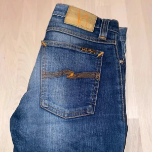 Blå Nudie Jeans W28 L32 - Säljer ett par blåa Nudie Jeans tight long john med unik wash. Storlek: W28 L32, men de har ju tvättats så de har blivit lite mindre, ca W27 L30/31. Sparsamt använda utan några skador eller slitage. Nypris: 1599 kr. Perfekta för dig som söker stiliga, hållbara och bekväma jeans. Hör gärna av dig om du har några frågor eller liknande🙌
