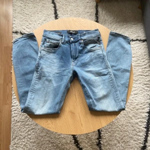 Replay ljusblå - Säljer ett par snygga ljusblå jeans från Replay med klassisk femficksdesign och diskreta slitningar framtill🙌 Jeansen har raka ben och normal passform, med Replay-logga på bakfickan och läderpatch i midjan👖 Perfekt för dig som gillar stilrena och bekväma jeans💯  Jeansen har Grover modell och har hyperflex material🪢 De har storleken W28 L30📐  Vid frågor: Meddela oss!📩