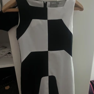 Svartvit rutig klänning KappAhl - Cool svartvit klänning från KappAhl med grafiskt rutigt mönster. Ärmlös modell med rund hals och dragkedja bak. Perfekt för dig som gillar retrostil och vill sticka ut med en unik look.