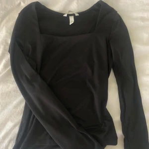 Långärmad svart topp - Super snygg långärmad svart topp, med fin ringning i halsen. Inga deffekter