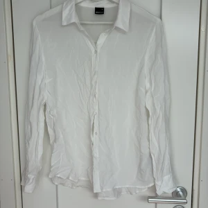 Vit skjorta från Gina Tricot, stl 40 - Vit skjorta från Gina Tricot i storlek 40. Skjortan har lång ärm, krage och knäppning framtill. Tillverkad i ett tunt och lätt material som ger en luftig känsla. Perfekt att styla med jeans eller kjol för en clean look.
