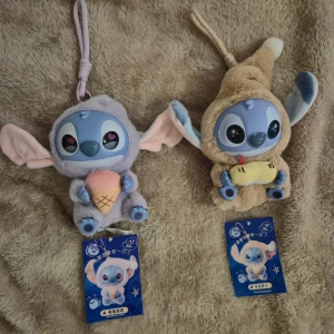 Söt Stitch handväska med plysch - Supergullig liten handväska i form av Stitch från Lilo & Stitch. Väskan är gjord i mjuk plysch, finns i ljuslila och beige med stora öron och broderade detaljer. Ena håller en glass, den andra en banan. Perfekt att hänga på väskan eller använda som liten accessoar. Säljer 2st för 450kr