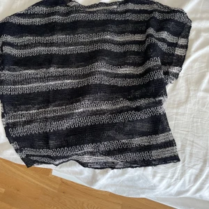 Svart och vit stickad topp med ränder - Säljer en luftig och transparent stickad topp i svart och vitt med horisontella ränder. Toppen har en boxig passform och är ärmlös, perfekt att styla över ett linne eller bikini. Materialet är stickat och ger en cool, avslappnad vibe. Första är svart med vita ränder, andra är helt svart och den tredje har glitter på sig. 