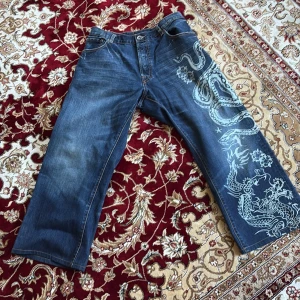 Ed Hardy jeans - Riktigt snygga ed Hardy jeans som sitter straight/baggy. De är reworkade från w38 men passar nu bra på 32 ish. 94 cm ytterben, midja 38 cm, 68 innerben, 28 benöppning. Modellen är 179 65kg De har en otroligt fin design så hoppas att någon med sjuk swag kan få bära dessa😁kan mötas i sthlm, skriv vid minsta fråga!