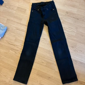 Svarta straight jeans Dr Denim XS/32 - Säljer ett par svarta straight fit jeans från Dr Denim, modell Dixy Straight. Klassisk femficksdesign, bälteshällor och dragkedja. Snyggt minimalistiska och passar till allt. Materialet är jeans i solid svart färg.