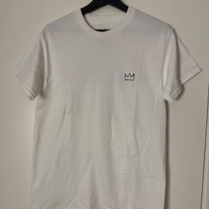 Vit Hov1 t-shirt merch  - Vit t-shirt från Hov1 med en liten krona på bröstet och stort färgglatt turnétryck på ryggen med texten 'Vi Dansar Vidare I Livet' och turnédatum.  Denna köptes på deras sista konser på Gärdet i Stockholm. Denna har inte kommit till användning eller ens testats och är väldigt säker på att den inte heller kommer komma till nån användning av mig därför känns det bättre att sälja den till någon som verkligen vill ha den. Pris går att diskutera!