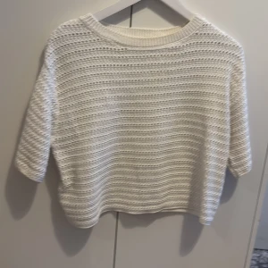 Vit stickad tröja från MNG - Vit stickad tröja från MNG med kort ärm och rund hals. Tröjan har ett snyggt hålmönster i horisontella ränder och är lite boxig i modellen. Perfekt till vår och sommar för en chill och stilren look.