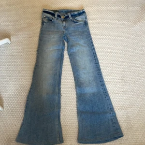 Bootcut jeans från Cheap Monday - Snygga ljusblå bootcut jeans från weekday och modellen är Cheap monday. Jeansen har en lätt tvättad look. Perfekta för dig som gillar retrovibbar och vill ha ett par jeans med lite vidare ben. Innerbenslängden är 73 cm se på bilden. Har inte används någon gång