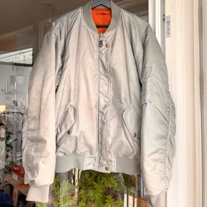 Grå och orange bomberjacka från urban outfitters - Grön-grå bomberjacka från urban outfitters som går att vända ut och in så den blir orange. Strl S enligt lappen på insidan men passar mig som oftast har L-XL. Perfekt jacka till hösten.