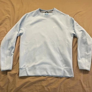 Ljusblå Nike NOCTA sweatshirt - Snygg ljusblå sweatshirt från Nike NOCTA med klassisk rund hals och diskret Nike-logga på bröstet. Perfekt för en clean och sportig look. Använt en eller två gånger. Storlek S män. Pris kan diskuteras. Skickas inom 1-3 dagar.