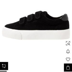 Svarta sneakers med kardborreband, even odd  - Stilrena svarta sneakers med bred vit platt sula och tre smidiga kardborreband. Ovandelen är i manchestertyg och hälen har en snygg detalj i svart skinn. Perfekta för en clean och avslappnad look. Säljer dom för att jag har för breda fötter så får skoskav. Efter som jag inte har kunnat gå i dom så har jag inte använt dom mer än 3,4 gånger. I korta sträcker för kan inte gå i dom. Så dom är som helt nya!!