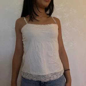 Vit spetsdetaljerad linnetopp - Säljer en söt vit linnetopp med tunna axelband och fina spetsdetaljer längs både överkant och nederkant. Toppen har en rak passform och är perfekt för en avslappnad och trendig look. Materialet känns lätt och luftigt. Storleken är M men passar mig fint som brukar har XS/S 💗💗