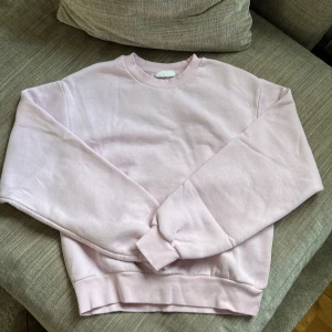 Ljusrosa sweatshirt från Gina Tricot - Supermjuk ljusrosa sweatshirt från Gina Tricot, basically basics-kollektionen. Klassisk modell med rund hals, ribbade muddar vid ärmslut och nederkant. Perfekt för chill dagar och enkel att matcha med jeans eller leggings.