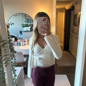 Vit omlottstickad tröja med knyt - Supermjuk vit stickad omlott-tröja med knyt i sidan och v-ringad hals. Perfekt för lager-på-lager. Enkel att styla med både jeans och kjol. Hör av dig om du har några frågor! 🫶🏼💕