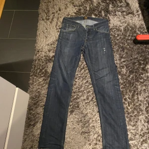Lee Daren Button Fly jeans blå W29 L32 - Snygga mörkblå jeans från Lee, modell Daren Button Fly. Klassisk femficksdesign med raka ben och normal passform. Jeansen har Lee-lappen bak i midjan och är gjorda i slitstarkt bomullsmaterial. Perfekt för dig som gillar stilrena och tidlösa jeans.