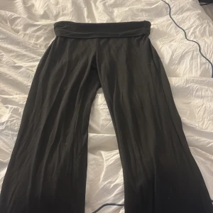Svarta vida mjukisbyxor - Svarta mjukisbyxor med bred, vikt midja och vida ben. Sköna och stretchiga, perfekta för chill eller träning. Materialet känns mjukt mot huden och ger en avslappnad vibe.