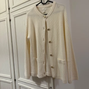 Beige stickad kofta med knappar - Säljer en beige stickad kofta med rund halsringning och snygga knappar framtill. Koftan har två små fickor och långa ärmar. Perfekt att slänga på sig när det är lite kyligt ute.