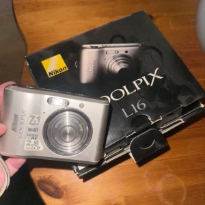 Coolpix L16 - Nikon Coolpix L16 digitalkamera med originalkartong. 7.1 megapixlar, 2.8" LCD-skärm, 3x optisk zoom och anti-skakfunktion. Kameran ser ut att vara i gott skick med minimalt slitage. Perfekt för dig som vill ha en enkel och pålitlig kompaktkamera. Den är från 2008. Kolla gärna in coolpix l16 på TikTok för att se hur bilder blir. #vintage 