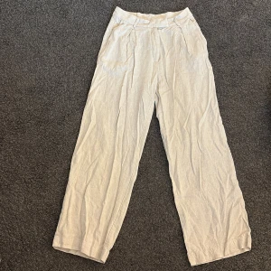 Beiga vida linnebyxor - Snygga och luftiga beiga linnebyxor med hög midja och raka, vida ben. 