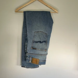 Nudie Jeans  - Nudie Jeans i storlek W36/L34. Ljusblå denim med slim fit-passform och stretch som gör dem bekväma. Rätt slitna, därav det lägre priset. Nypris runt 1500–2000 kr.  Mått: A (midja): 45 cm B (lårvidd): 28 cm C (fotvidd): 19 cm D (innerbenslängd): 82 cm  Säljes för 149kr. 