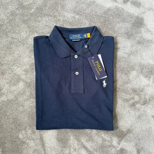 Pikétröja från Ralph Lauren - Ralph Lauren Pike  📏 Storlek M herr  Axelbredd: 42cm Längd: 69cm  🔍 Skick Nyskick  Kommer med påse 🎨  Färg  Mörkblå  💬 Skriv om ni har några frågor