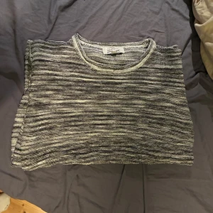 Randig stickad tröja från Skill - Säljer en stickad långärmad tröja från Skill i grått och vitt med randigt mönster. Tröjan har rund halsringning och är perfekt för dig som gillar en chill och enkel stil. Passar bra till jeans eller mjukisbyxor. Perfekt för hösten! 