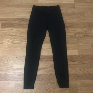 Svarta leggings från SOC - Svarta leggings från SOC med hög midja och tight passform. Tillverkade i ett stretchigt syntetmaterial som passar perfekt för träning. Snygg och enkel design utan synliga detaljer eller mönster.