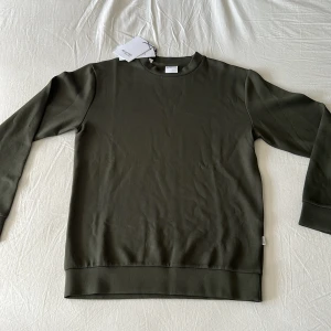 Mörkgrön sweatshirt från Selected Homme - En stilren mörkgrön sweatshirt från Selected Homme i mjuk bomullsblandning. Tröjan har rund halsringning, långa ärmar och ribbade muddar vid ärmslut och nederkant. Perfekt för en clean och avslappnad look. Aldrig använd.