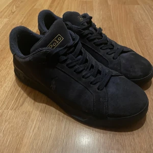 Blåa mockasneakers Polo Ralph Lauren - Snygga svarta sneakers från Polo Ralph Lauren i mjuk mörkblå mocka med diskret logga på sidan och guldiga Polo-detaljer på plösen och hälen. Klassisk rund tå, svarta snören och platt sula. Perfekta för en clean och stilren look. Skorna är i fint skick men har ett litet hål i höger sko på insidan över stortån. Detta är inget som syns utifrån och jag kände inte av hålet innan jag kände med handen.Om du vill ha flera bilder är det bara att säga till 🙌👌 NYPRIS 1795 KR! 