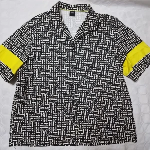 Mönstrad skjorta från BOSS med gula detaljer - Säljer en svartvit skjorta från BOSS med grafiskt mönster och coola gula paneler på ärmarna. Skjortan har korta ärmar, klassisk krage och en loose fit som ger en avslappnad vibe. Perfekt för dig som gillar att sticka ut med din stil. Sällsynt och äkta. 