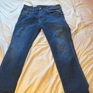 Blå Replay Anbass jeans herr - Säljer ett par snygga blå Replay Anbass jeans i klassisk femficksmodell. Jeansen har raka ben, normal passform och är tillverkade i mjukt stretchigt jeanstyg. Fina detaljer med Replay-logga på fickan och bakfickor med dekorativa sömmar. priset är inte hugget i Sten