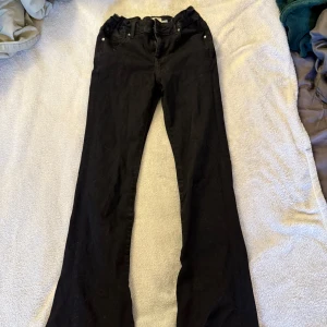 Svarta flare jeans från 157 - Svarta jeans från 157 i modellen Skippy Flare med snyggt utsvängda ben. Byxorna har klassisk femficksdesign, justerbar midja med resår och knapp, samt dragkedja. Perfekta för dig som gillar en trendig och bekväm look.