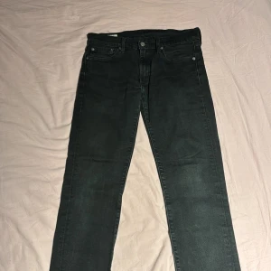 Svarta Levi's 501 jeans straight fit - Svarta Levi's 501 jeans med klassisk straight fit och fem fickor. Jeansen har en snygg svart läderpatch bak i midjan och silverfärgade knappar. Materialet är slitstarkt denim och passformen är normal. Perfekt för dig som gillar tidlös stil.