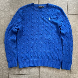 Blå kabelstickad Ralph Lauren tröja (Herr M) - Riktigt fin blå kabelstickad tröja från Ralph Lauren. Tröjan är i gott skick och har knappt använts. Nypris ligger på ca 2200kr
