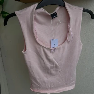 Ljusrosa ärmlös topp  - Supersöt ljusrosa topp som är ärmlös och rundad halsringning. Toppen har en liten rosett framtill och är gjord i mjuk bomull. (Orginalpriset är 179 men den är helt ny och prislappen kvar)