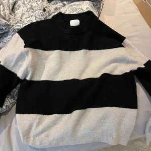 Randig svart och vit stickad tröja - Säljer en stickad tröja med breda svarta och vita ränder. Tröjan har rund halsringning och långa ärmar. Perfekt för dig som gillar en enkel men ändå snygg look med kontrasterande färger💞