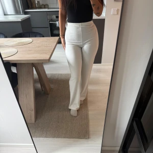 Vita vida byxor från Nelly - Säljer ett par snygga vita byxor från Nelly i storlek S. Byxorna är högmidjade med en vid passform och har en lätt texturerad yta. Perfekta att styla med en tight topp eller oversized hoodie. Superfräscha och stilrena!