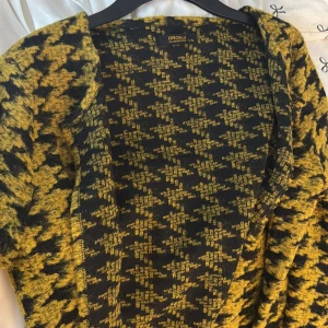Gul och svart rutig cardigan jacka Oroblu - Säljer en oversized cardigan jacka från Oroblu i gul och svart rutig design. Jackan är stickad och har lång ärm. Köptes utomlands för 1000kr. 