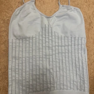 Ljusblå linnetopp med hålmönster - Säljer en ljusblå linnetopp med tunna axelband och vertikalt hålmönster framtill. Köpt utomlands, sitter tajt och snyggt på kroppen, storlek xs. 